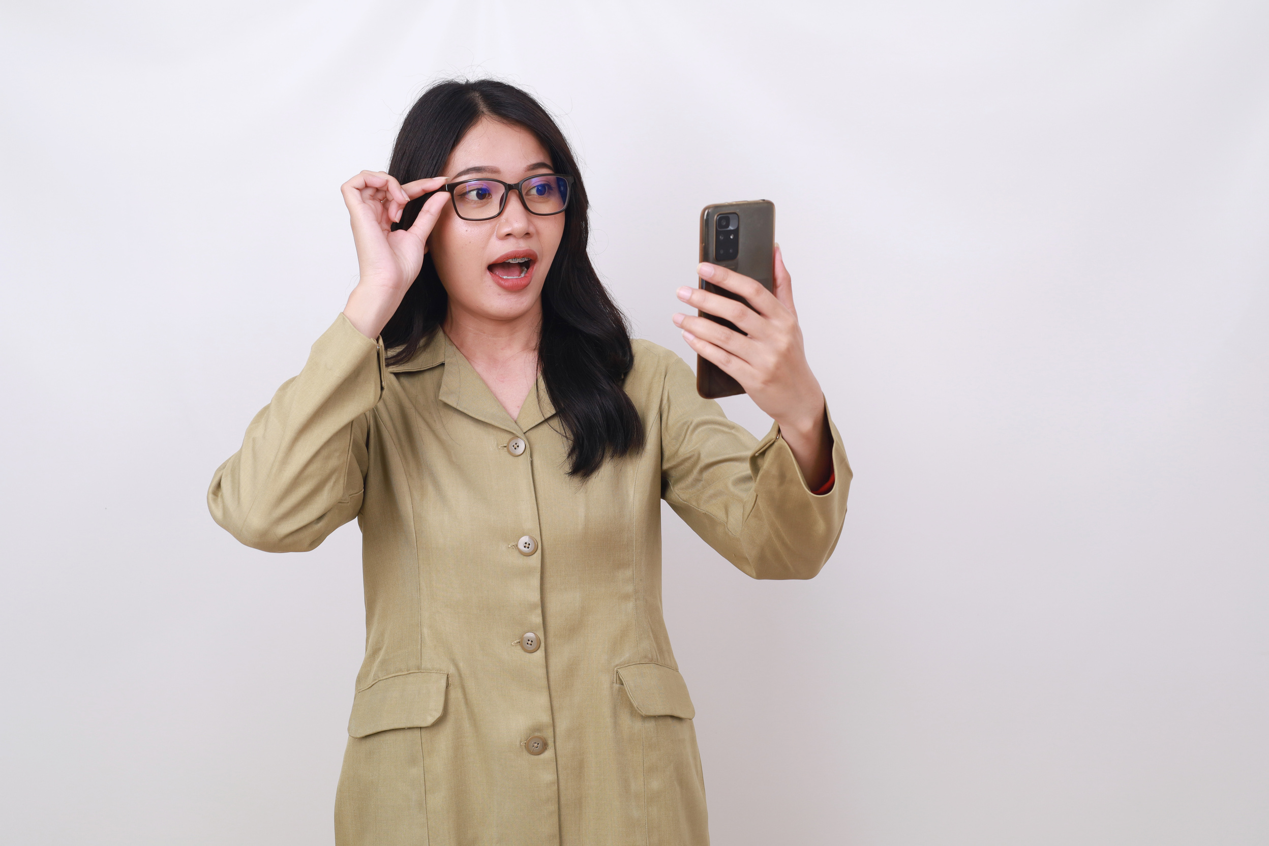 Wow surprised young Indonesian civil servant woman getting good news from her cell phone